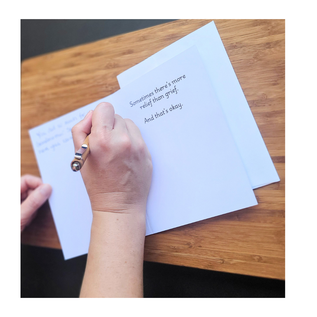 Close up view of a hand writing in a sympathy card for a loved one.